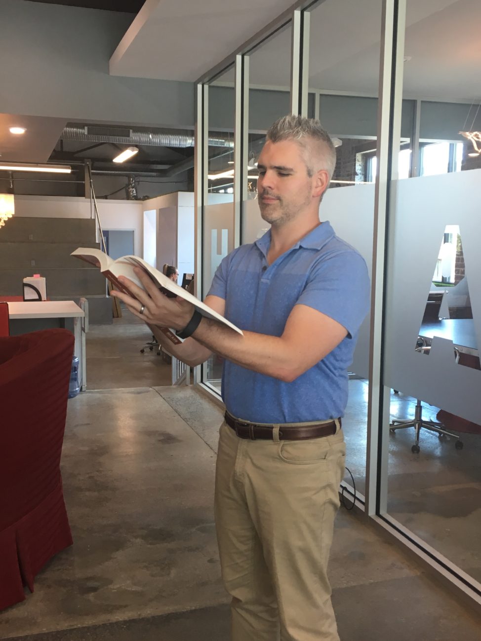 man in office holding and looking at an open book