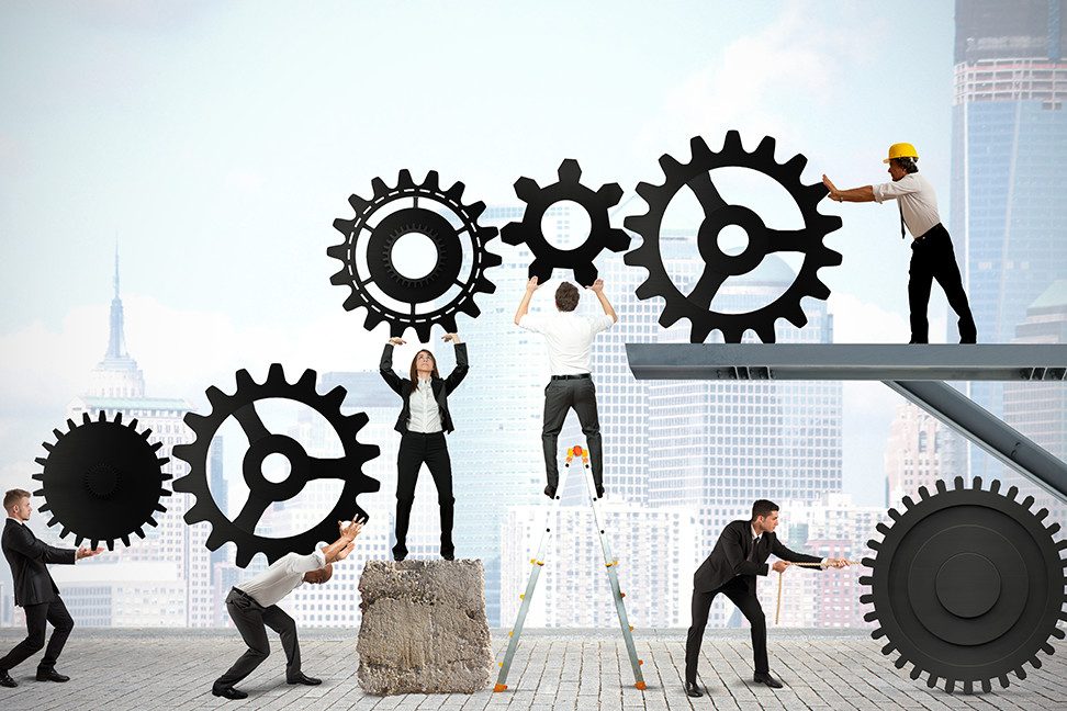 Business people turning giant gears together